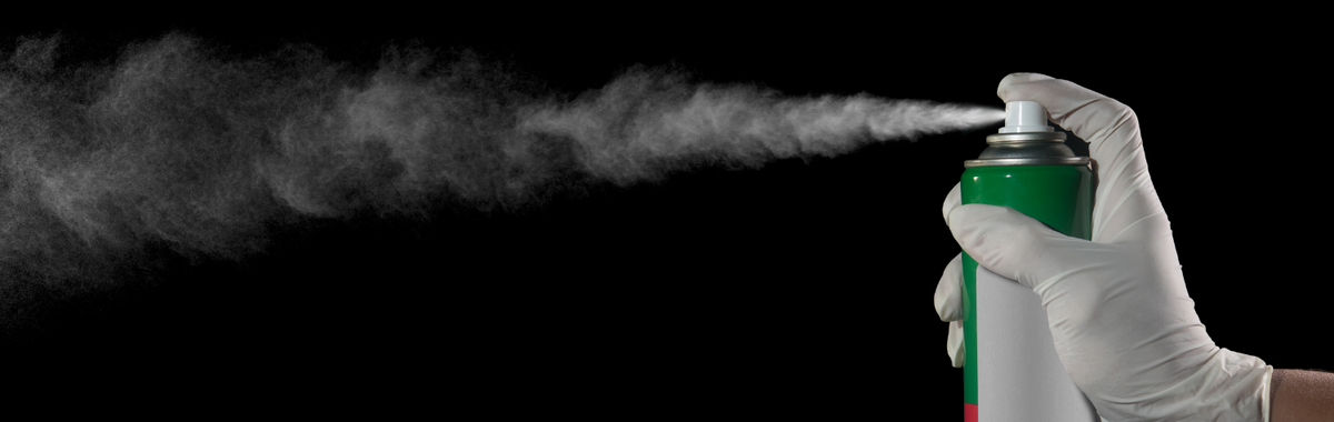 Gloved hand spraying an aerosol insecticide