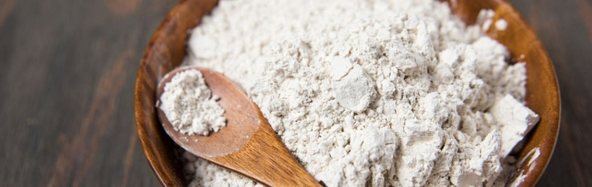 Wooden bowl and spoon filled with white diatomaceous earth powder
