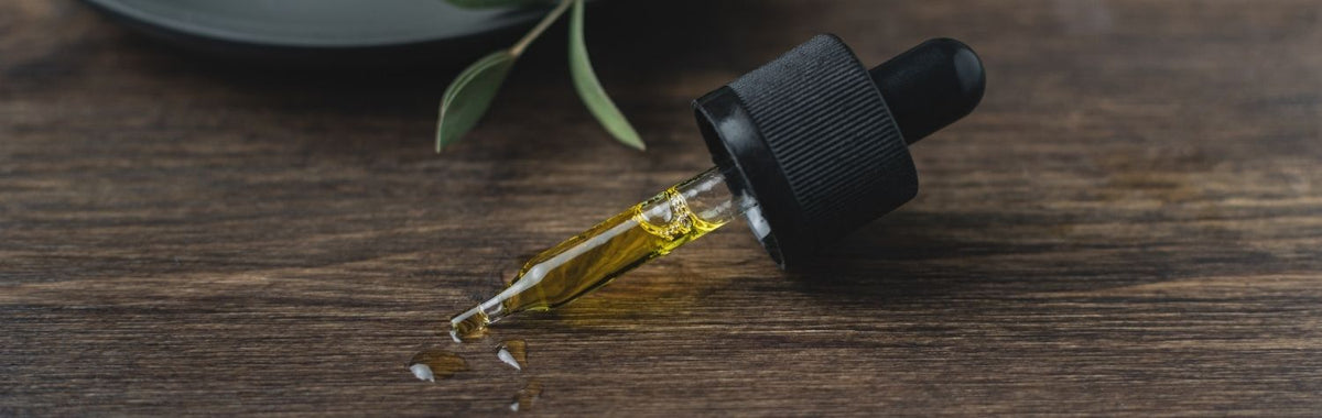 Dropper dispensing essential oil onto a wooden table