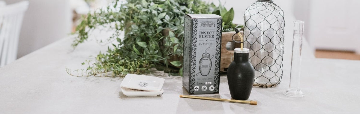 Dr. Killigan's Insect Buster diatomaceous earth duster on a white table beside greenery