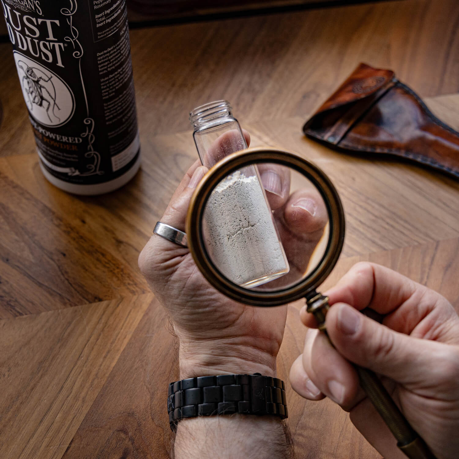 man with a magnifying glass looking at a glass bottle with powder inside it.