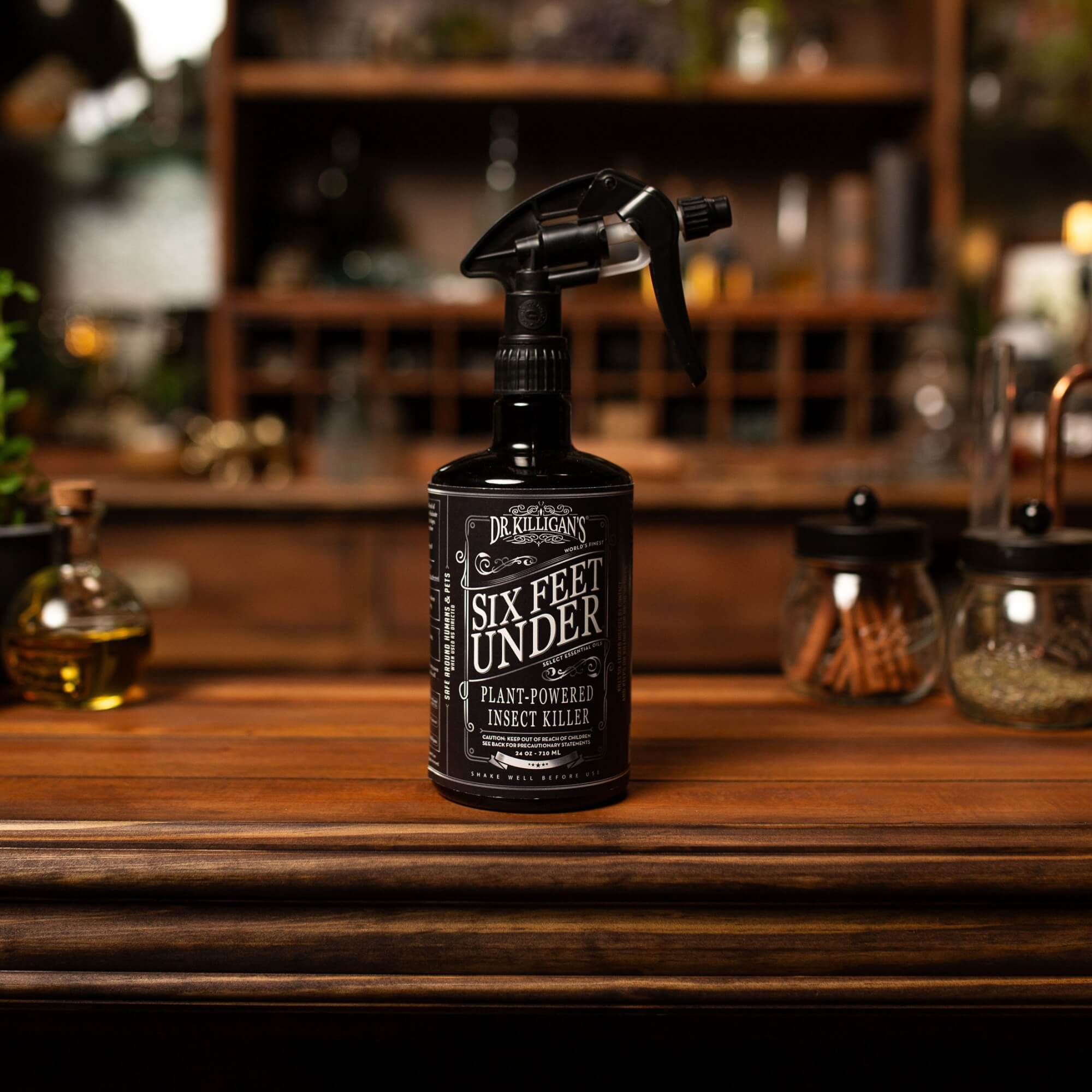 Black spray bottle labeled 'Six Feet Under' on a wooden surface with a blurred background