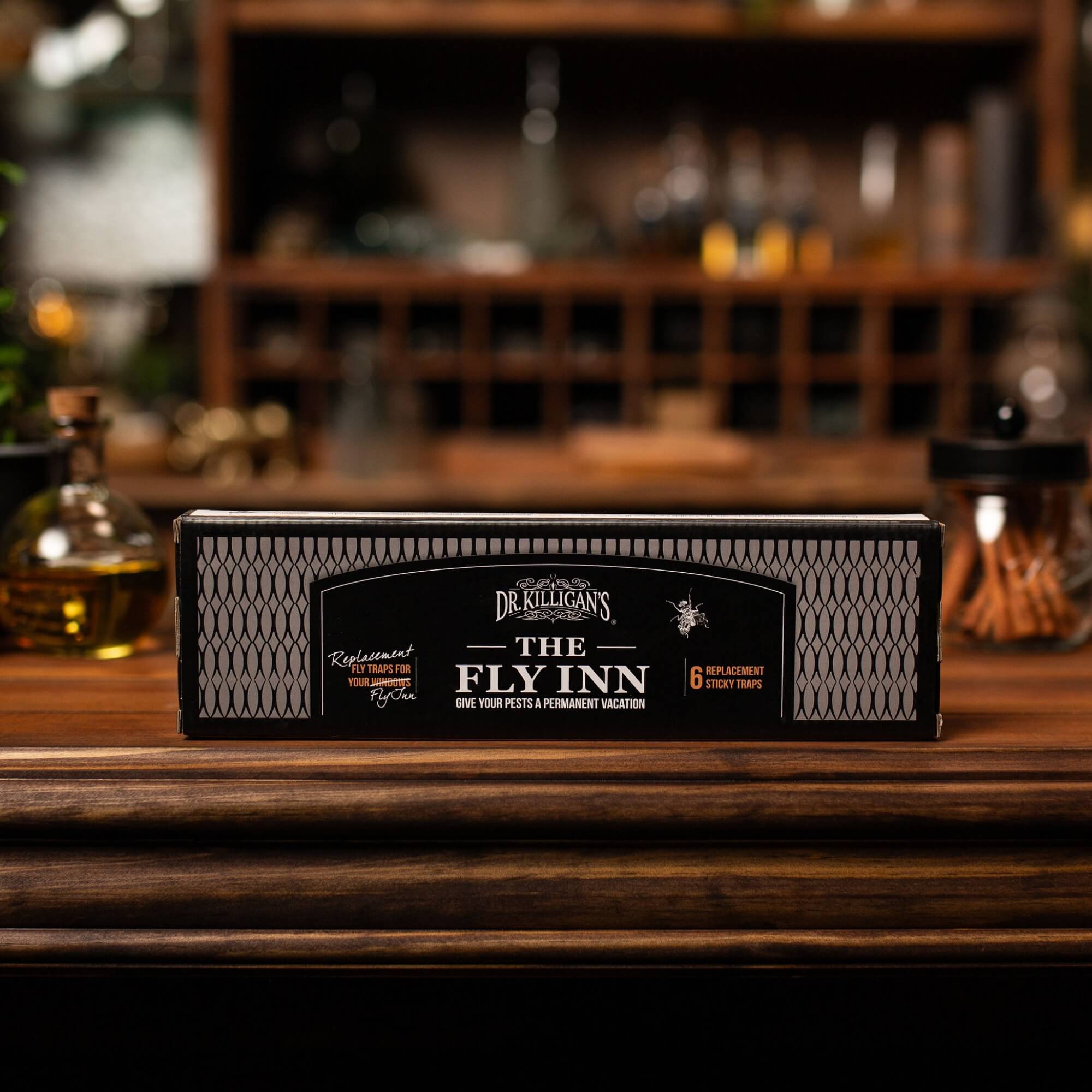 Dr. Killigan's The Fly Inn refills packaging on a wooden surface with a blurred bar background