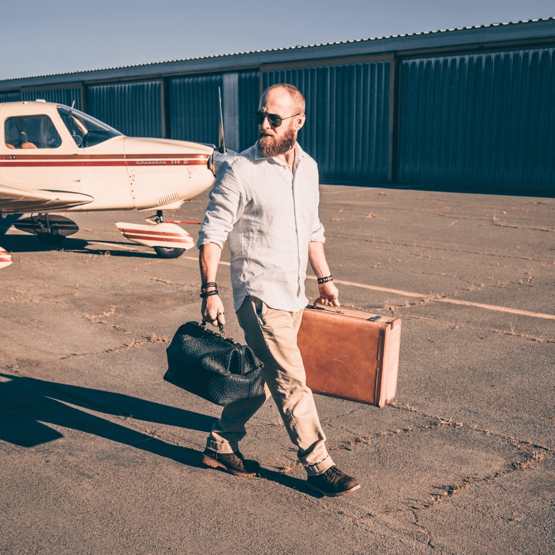 Dr. Killigan at a small airport carrying luggage and walking away from a plane